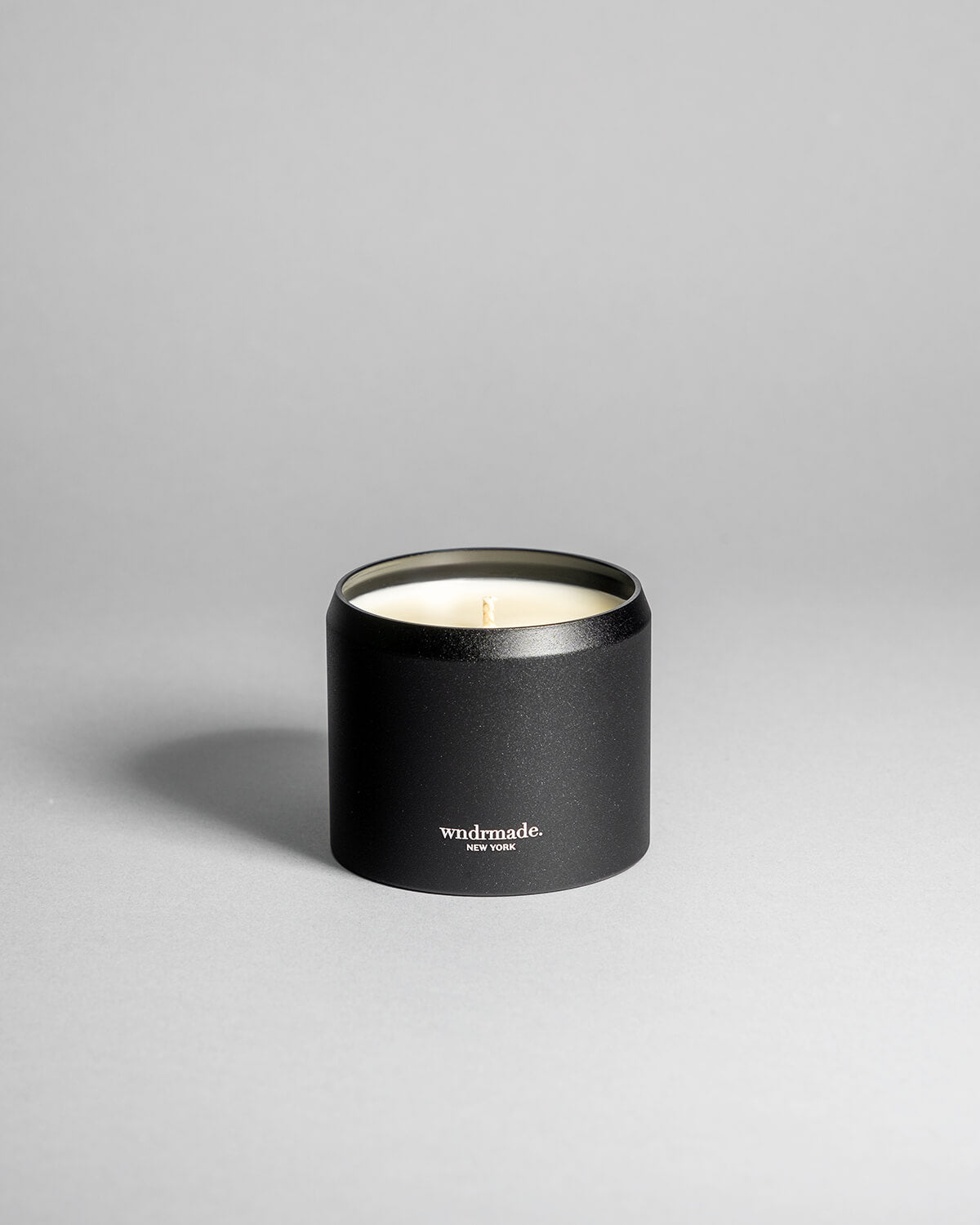 Hinoki candle in a black minimalist tin, featuring a rich, resinous wood aroma with a distinctive brightness. Infused with blue cypress, rose, yuzu, and balanced essential oils for a fresh, welcoming scent. Made with coconut/soy wax, essential oils, and botanical extracts.