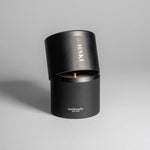 Hinoki candle in a black minimalist tin, featuring a rich, resinous wood aroma with a distinctive brightness. Infused with blue cypress, rose, yuzu, and balanced essential oils for a fresh, welcoming scent. Made with coconut/soy wax, essential oils, and botanical extracts.