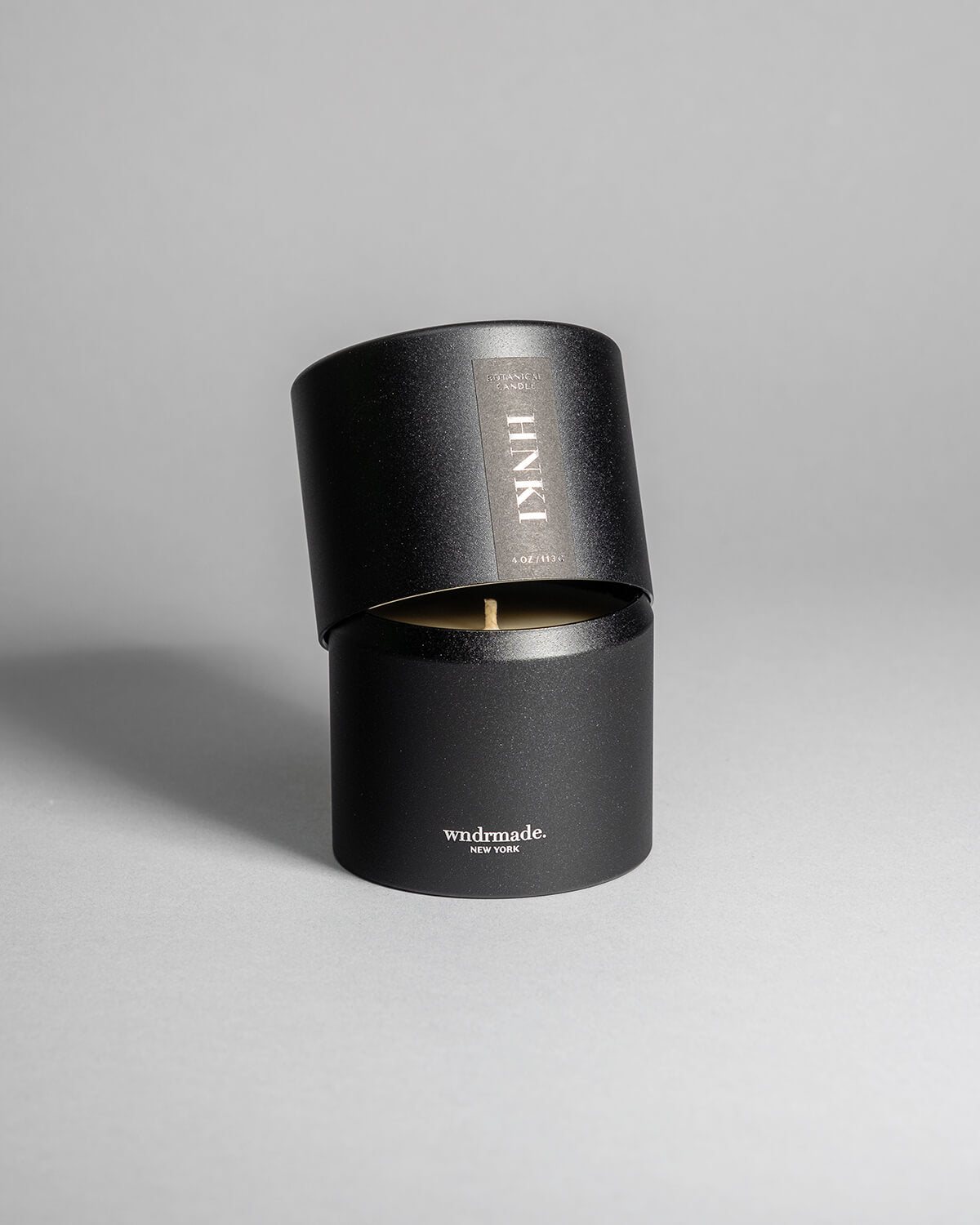 Hinoki candle in a black minimalist tin, featuring a rich, resinous wood aroma with a distinctive brightness. Infused with blue cypress, rose, yuzu, and balanced essential oils for a fresh, welcoming scent. Made with coconut/soy wax, essential oils, and botanical extracts.
