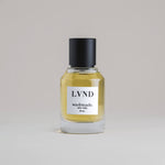 LVND Lavender 50 mL botanical perfume in a minimalist glass bottle with a matte black cap and golden hue, set against a pale gray backdrop.