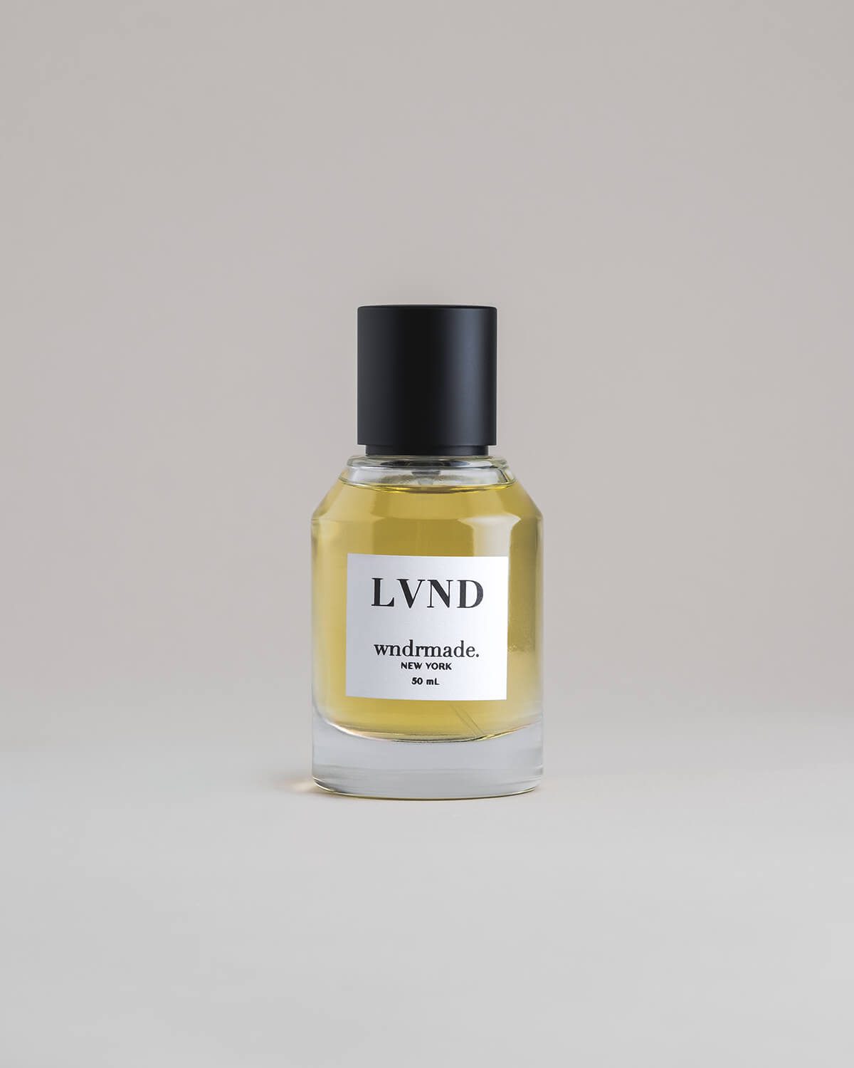 LVND Lavender 50 mL botanical perfume in a minimalist glass bottle with a matte black cap and golden hue, set against a pale gray backdrop.