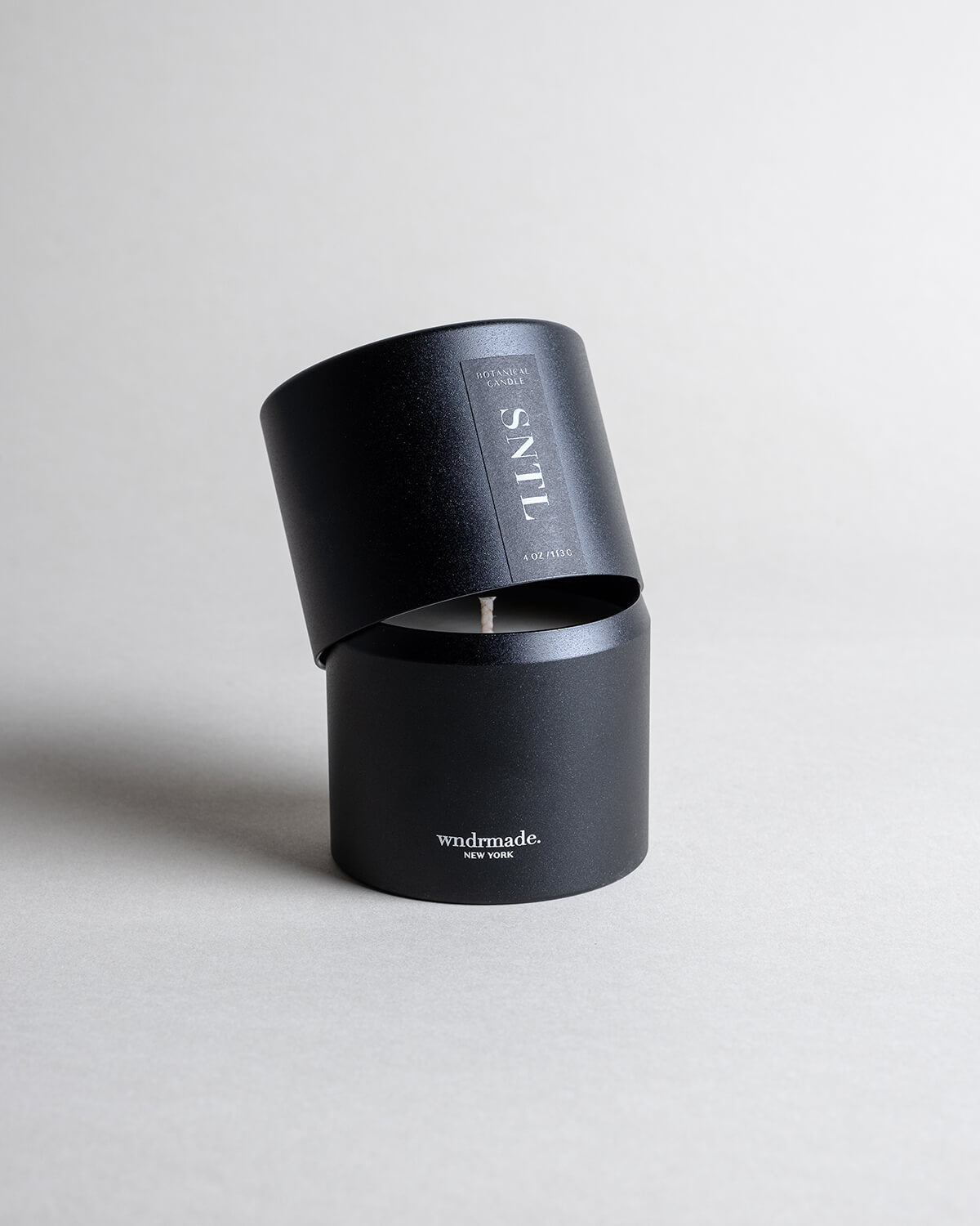 Santalum candle in a black minimalist tin, featuring sweet, rich, and luxurious sandalwood with a silky, smooth aroma. A warm, ethereal fragrance that arouses the senses and evokes timeless memories. Made with coconut/soy wax, essential oils, and botanical extracts.