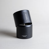 Santalum candle in a black minimalist tin, featuring sweet, rich, and luxurious sandalwood with a silky, smooth aroma. A warm, ethereal fragrance that arouses the senses and evokes timeless memories. Made with coconut/soy wax, essential oils, and botanical extracts.