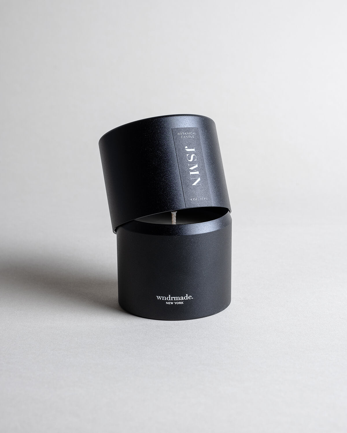 Jasmine candle in a black minimalist tin, featuring a sultry, seductive, honey-sweet aroma with natural complexity. Both arousing and calming, this scent celebrates intimate moments. Made with coconut/soy wax, essential oils, and botanical extracts.