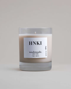 Wndrmade Hinoki candle in a clear heavy base glass without lid on a neutral surface.