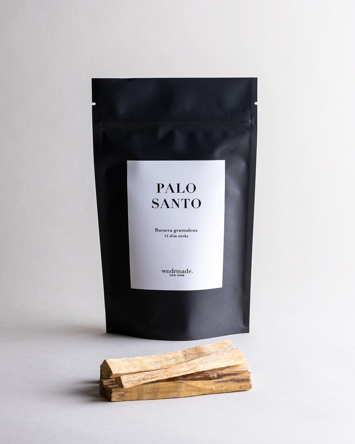 Black packaging of Palo Santo slim sticks (pack of 15 slim sticks) with slim wooden sticks on a light gray background