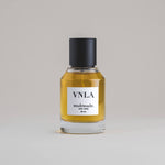VNLA Vanilla 50 mL botanical perfume in a minimalist glass bottle with a matte black cap and golden hue, set against a pale gray backdrop.
